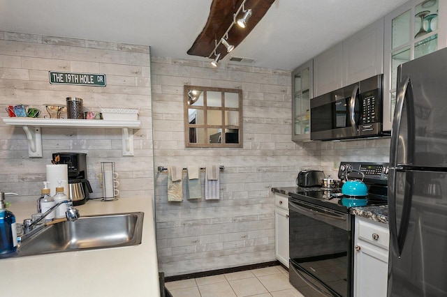 16 Oak Glen Dr, Galena, IL 61036 - kitchen featuring a sink, wooden walls, stainless steel appliances, light tile patterned floors, and visible vents