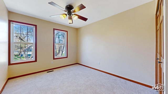 carpeted empty room featuring visible vents, ceiling fan, and baseboards