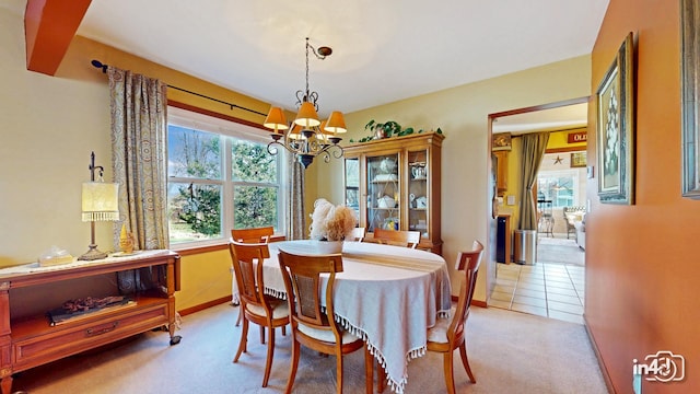 dining room with a notable chandelier, light carpet, and baseboards