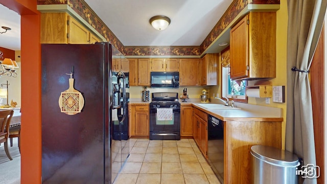 kitchen featuring light tile patterned floors, light countertops, brown cabinets, black appliances, and a sink