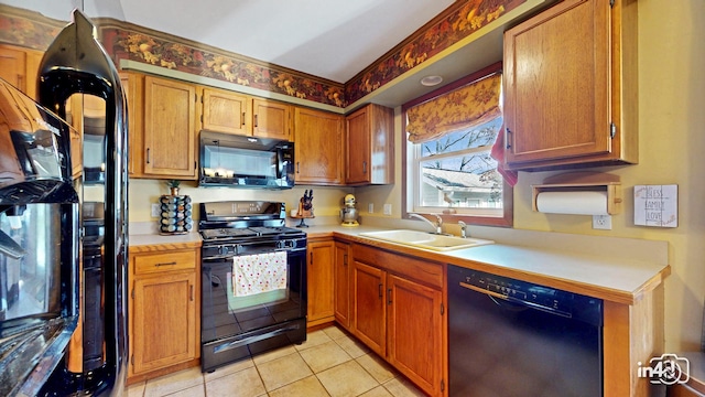 kitchen with a sink, brown cabinets, light tile patterned floors, black appliances, and light countertops