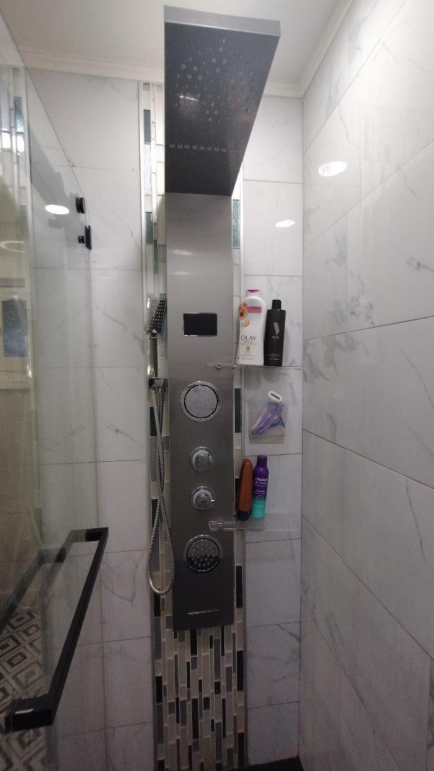 full bathroom with a tile shower and crown molding