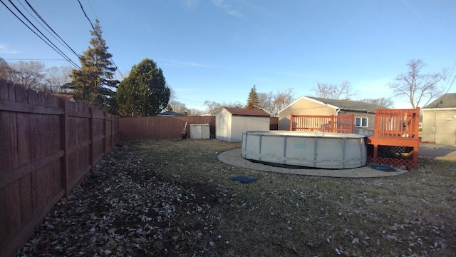 view of yard with a fenced in pool, a fenced backyard, a deck, an outdoor structure, and a shed