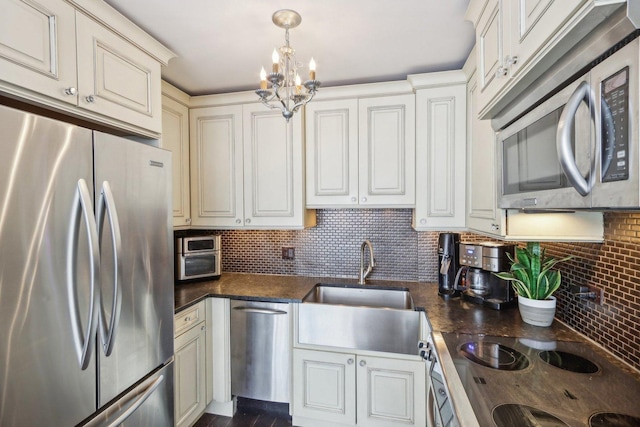 kitchen featuring stainless steel appliances, an inviting chandelier, backsplash, and dark countertops