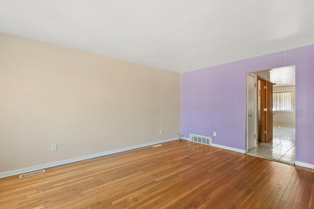 unfurnished room featuring baseboards, visible vents, and light wood finished floors