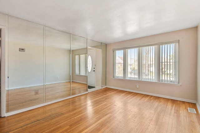 interior space with multiple windows, visible vents, wood-type flooring, and baseboards