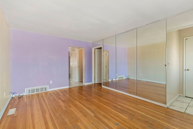 unfurnished bedroom featuring baseboards, visible vents, wood finished floors, and a closet