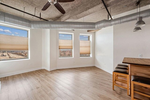 interior space with baseboards, ceiling fan, and wood finished floors