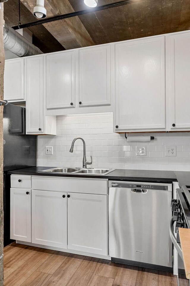 kitchen featuring light wood finished floors, stainless steel appliances, tasteful backsplash, white cabinetry, and a sink