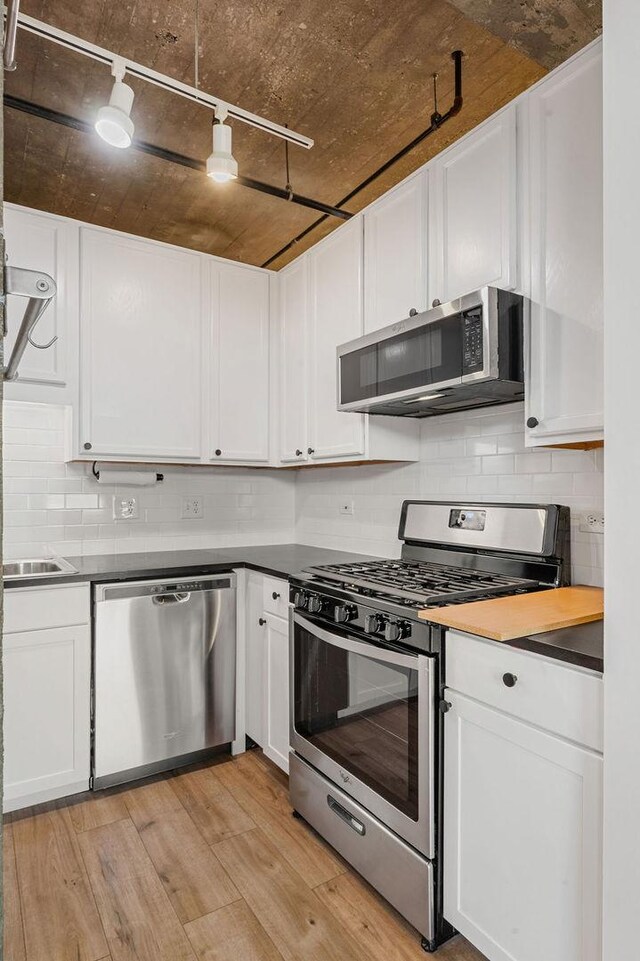 kitchen featuring white cabinetry, light wood-style flooring, backsplash, and appliances with stainless steel finishes