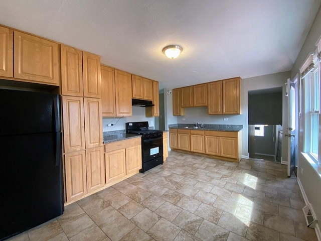 kitchen featuring baseboards, dark countertops, under cabinet range hood, a sink, and black appliances