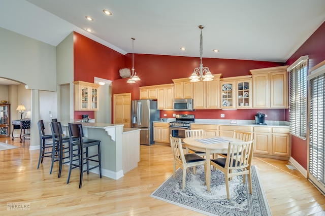 kitchen featuring a peninsula, a kitchen bar, stainless steel appliances, arched walkways, and glass insert cabinets