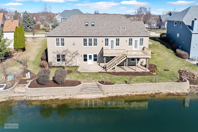 back of property with a patio, stairway, a residential view, a lawn, and a deck with water view