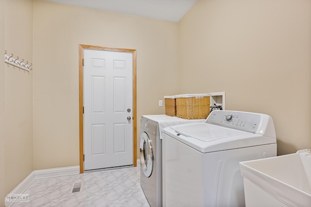 washroom with baseboards, separate washer and dryer, marble finish floor, a sink, and laundry area