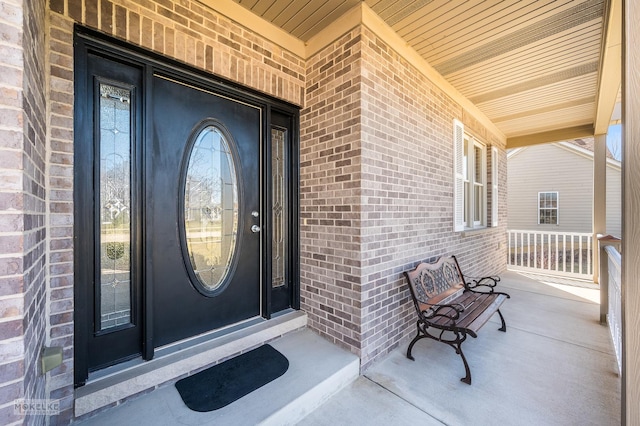 entrance to property featuring covered porch and brick siding