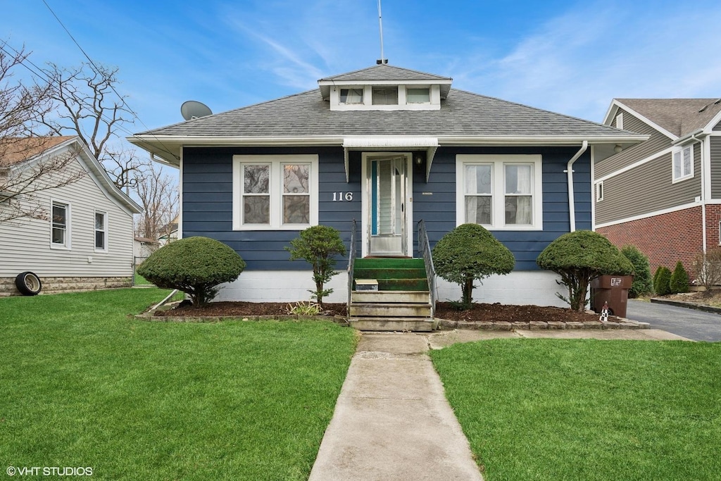 bungalow-style home with a front yard and a shingled roof