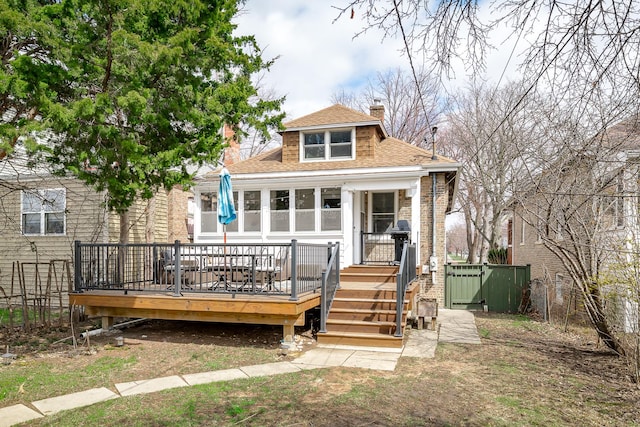rear view of property with a chimney, a gate, a wooden deck, fence, and a shingled roof