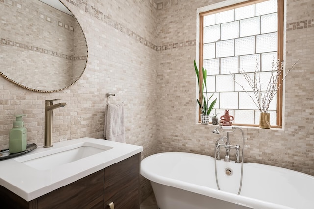 bathroom featuring a freestanding tub, vanity, and tile walls