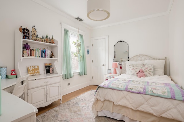 bedroom featuring ornamental molding, baseboards, light wood-type flooring, and visible vents