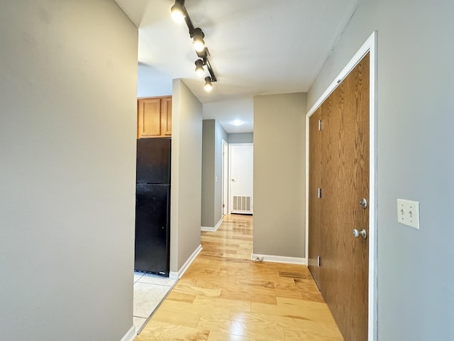 corridor featuring visible vents, baseboards, and light wood finished floors