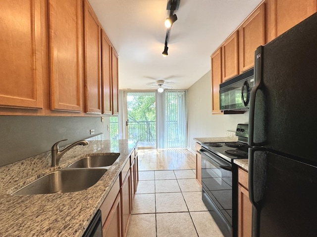 kitchen featuring light tile patterned floors, light stone countertops, brown cabinetry, black appliances, and a sink