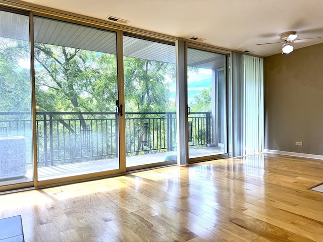 doorway to outside featuring wood finished floors, floor to ceiling windows, a ceiling fan, and baseboards