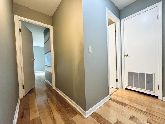 hallway featuring visible vents, baseboards, and wood finished floors