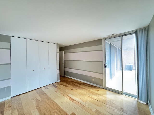unfurnished bedroom featuring baseboards, access to outside, light wood-type flooring, and visible vents