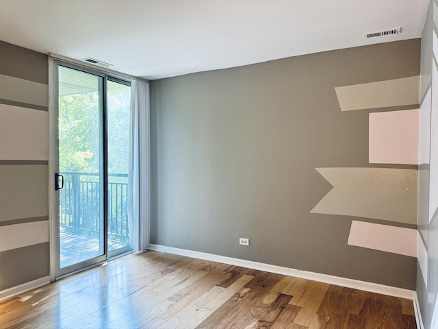 unfurnished room featuring wood finished floors, baseboards, visible vents, and plenty of natural light