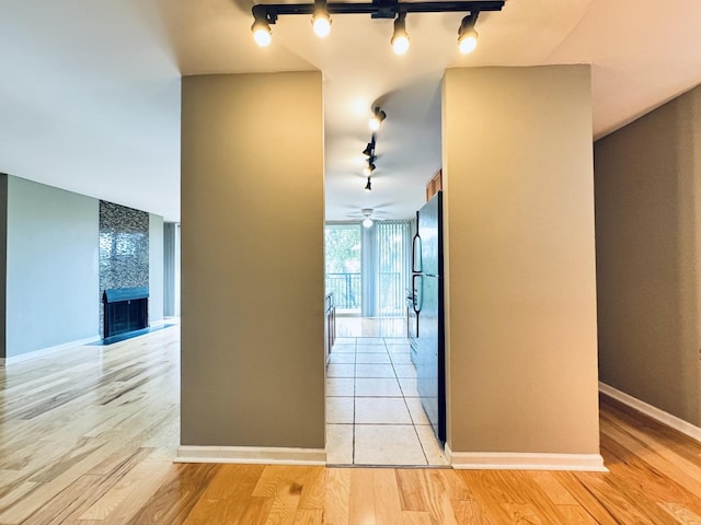 hall featuring track lighting, baseboards, and light wood-style floors