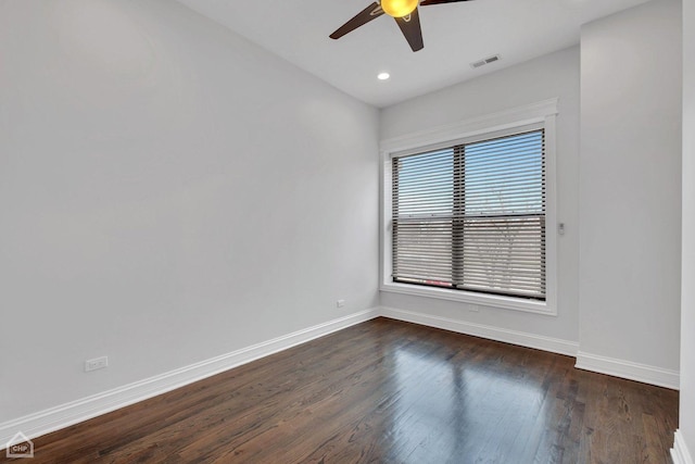 empty room with dark wood-style flooring, visible vents, ceiling fan, and baseboards