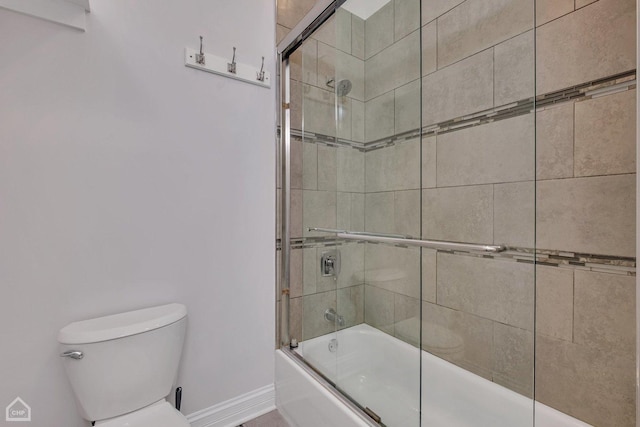 full bathroom featuring toilet, shower / bath combination with glass door, and baseboards