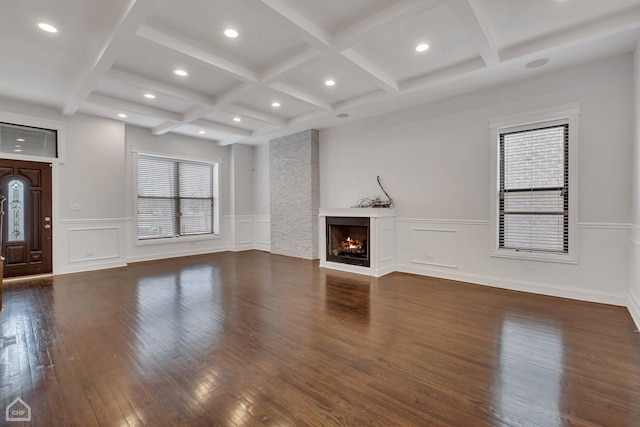 unfurnished living room featuring a warm lit fireplace, hardwood / wood-style flooring, beam ceiling, recessed lighting, and coffered ceiling