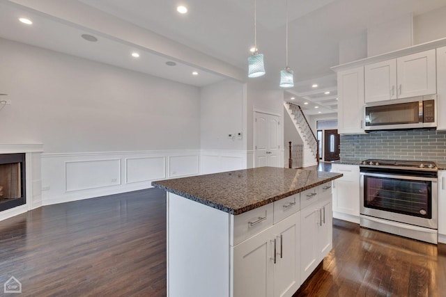 kitchen with white cabinets, a kitchen island, dark wood-style flooring, stainless steel appliances, and decorative backsplash