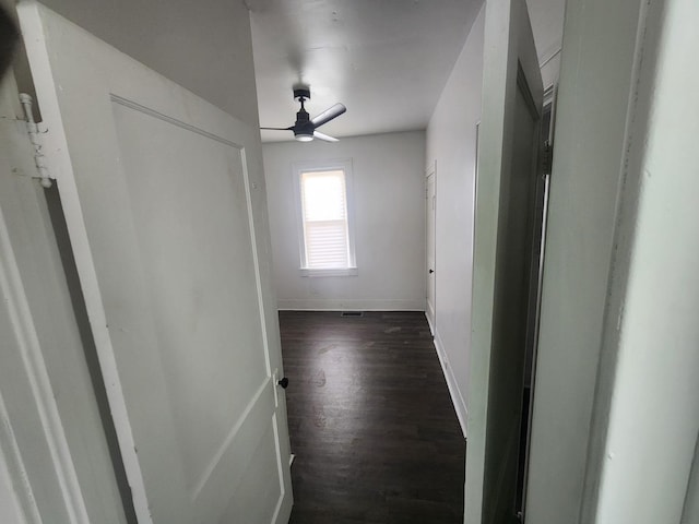 hallway featuring baseboards and dark wood-style flooring