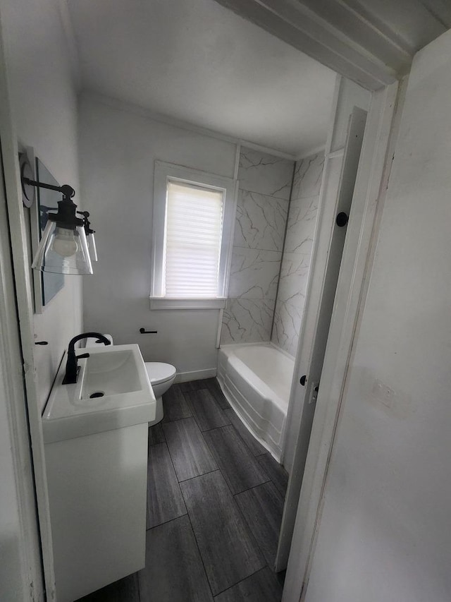 bathroom with vanity, wood finish floors, toilet, baseboards, and shower / tub combination