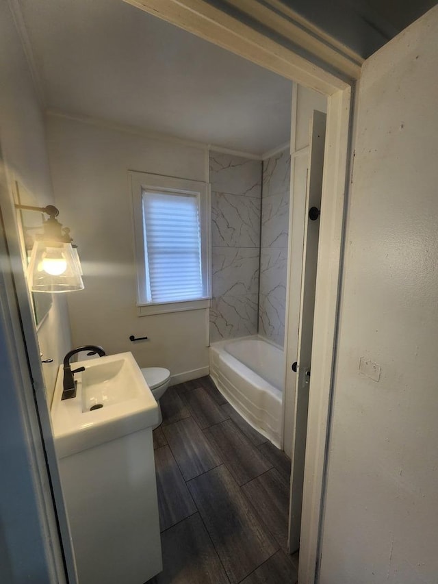 full bathroom featuring crown molding, washtub / shower combination, toilet, wood finish floors, and vanity