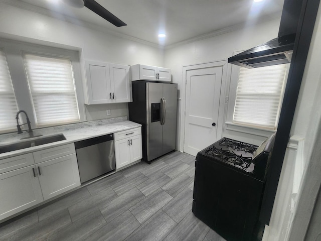 kitchen with light countertops, a sink, stainless steel appliances, wall chimney range hood, and ornamental molding