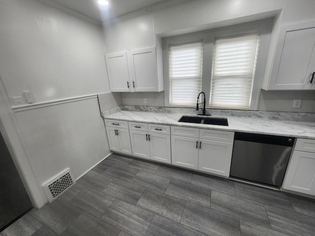 kitchen featuring stainless steel dishwasher, white cabinetry, visible vents, and a sink