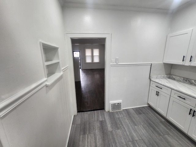 interior space with white cabinetry, ornamental molding, dark wood-type flooring, and visible vents