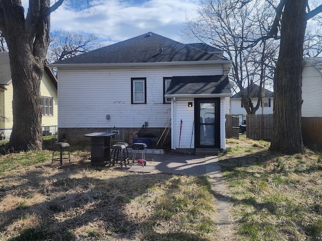 rear view of house with a shingled roof and fence