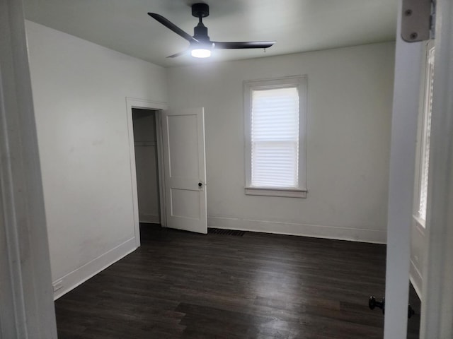 unfurnished room with baseboards, a ceiling fan, and dark wood finished floors