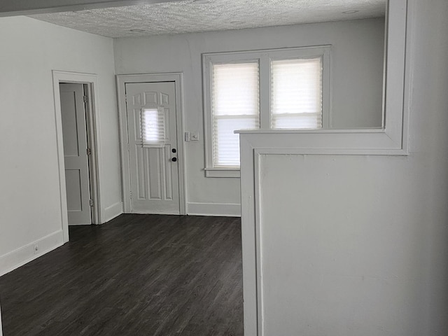 entrance foyer with dark wood-type flooring, baseboards, and a textured ceiling