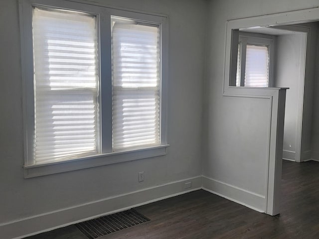 spare room featuring dark wood-type flooring, baseboards, and visible vents