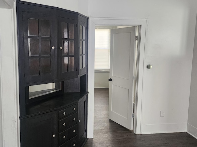 hall with dark wood-style flooring and baseboards
