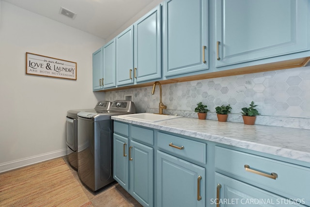 clothes washing area with washing machine and dryer, a sink, baseboards, visible vents, and cabinet space