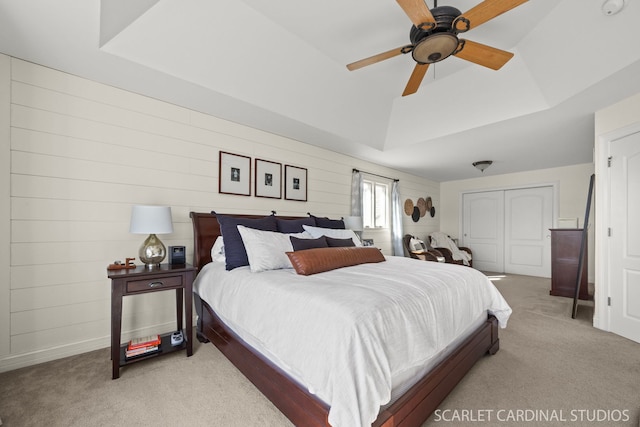 bedroom featuring a tray ceiling, baseboards, a closet, and light carpet