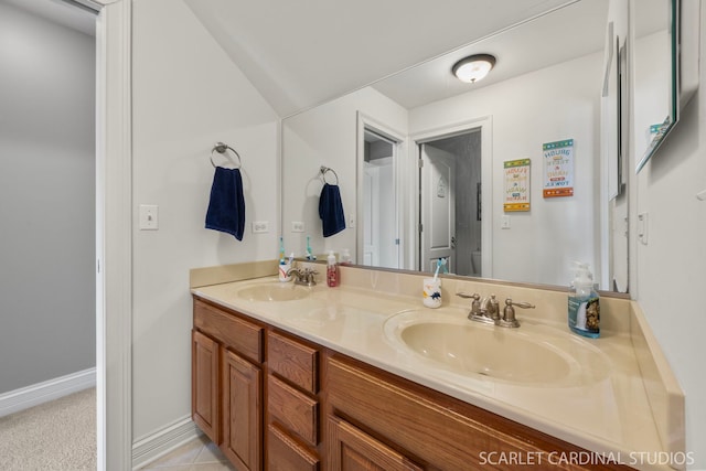 full bathroom with double vanity, a sink, tile patterned flooring, and baseboards
