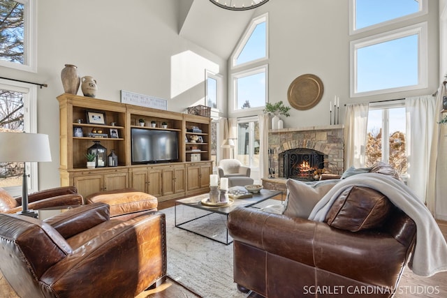 living area featuring a towering ceiling, a stone fireplace, and a wealth of natural light