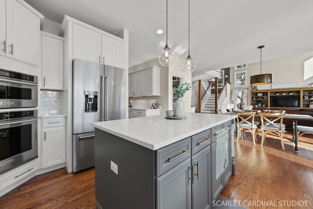 kitchen with decorative backsplash, appliances with stainless steel finishes, gray cabinetry, and dark wood-type flooring